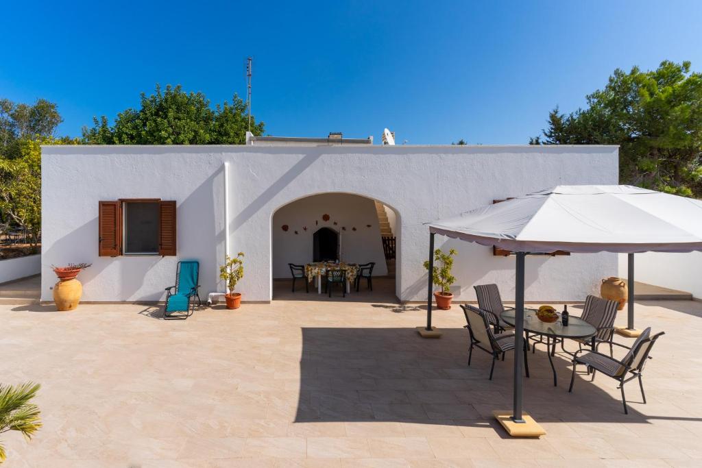 un patio con mesa y sombrilla en Villa Fioralba, en Castrignano del Capo