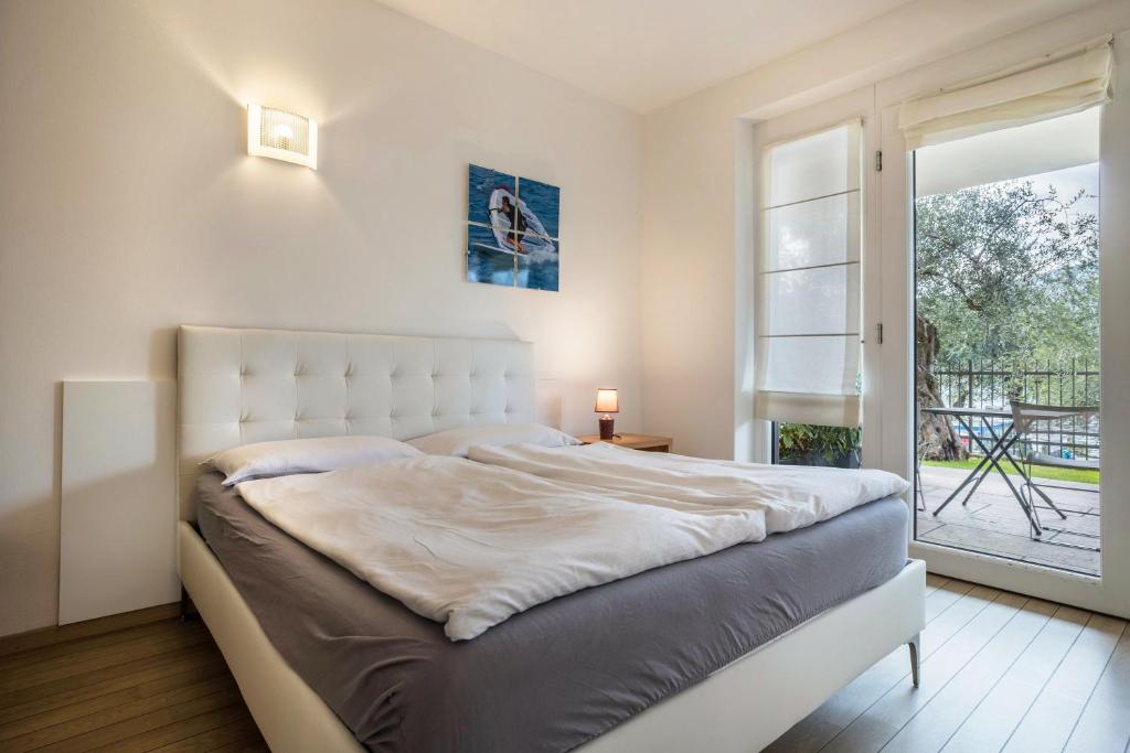 um quarto com uma cama branca e uma porta de vidro deslizante em Mono Vista Lago Villa Treccani em Malcesine