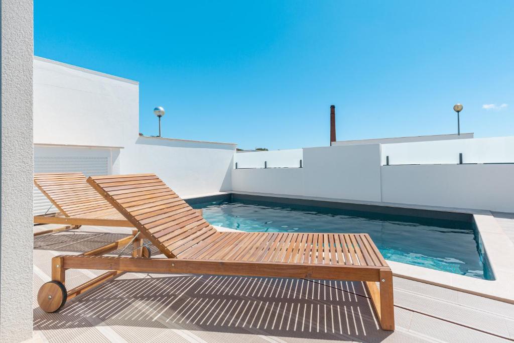 a wooden chair sitting next to a swimming pool at Villa Tapisco in Lourinhã