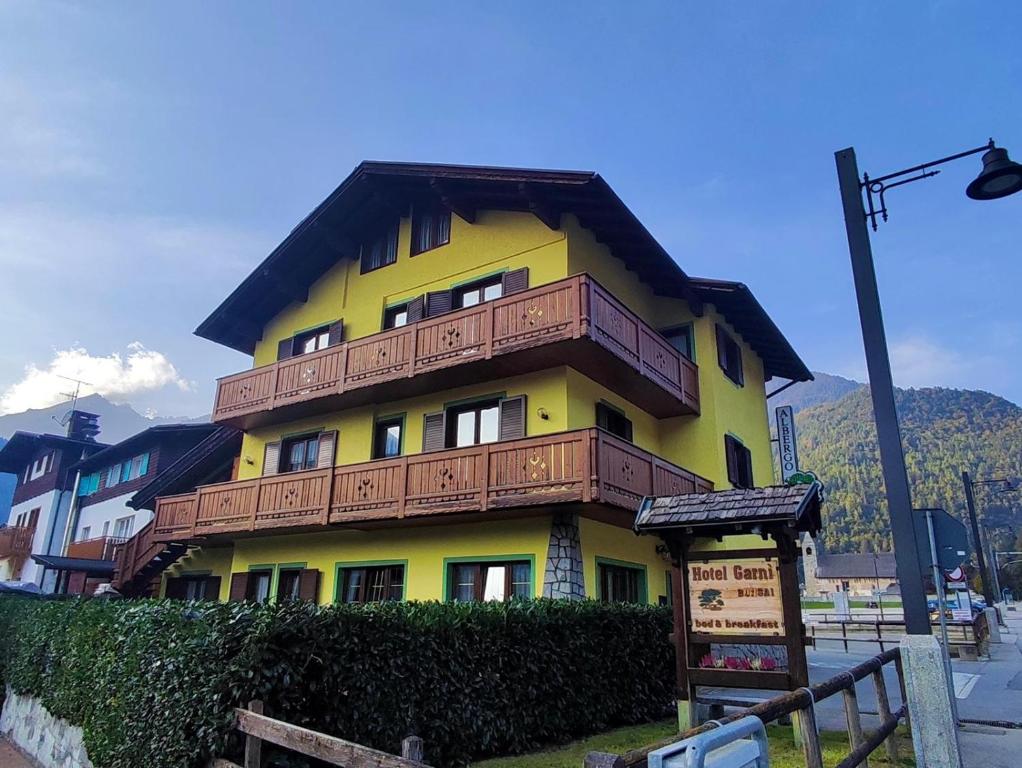 ein gelbes Gebäude mit Holzbalkonen darüber in der Unterkunft Garnì Bonsai in Pinzolo