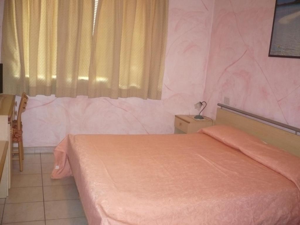 una camera con letto rosa e finestra di Rosa Hotel a Capoterra
