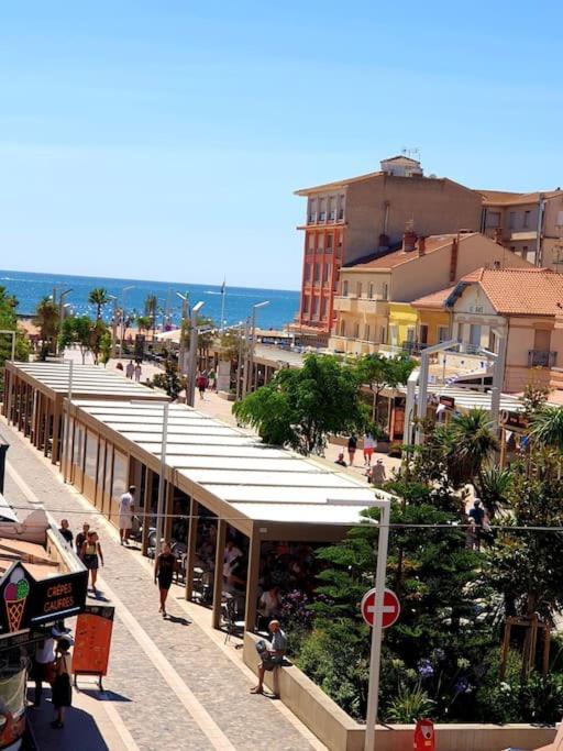 un groupe de personnes marchant dans une rue avec des bâtiments dans l'établissement hyper-centre plage à 100 mètres, à Valras-Plage