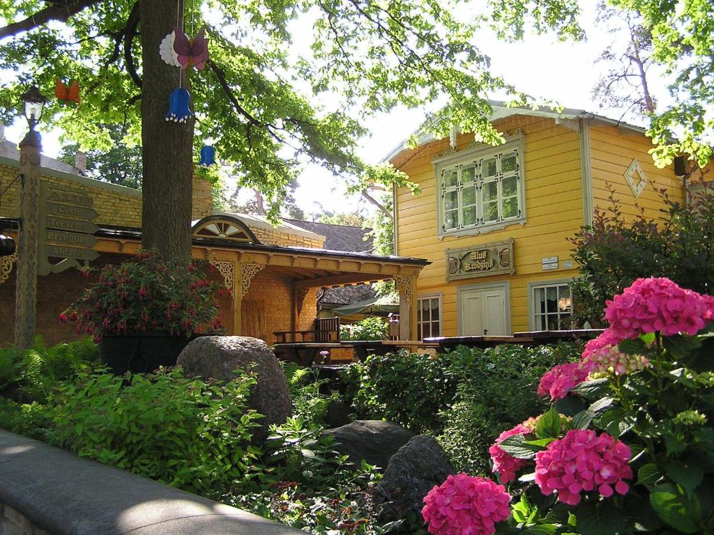 una casa amarilla con flores delante en Majoru Promenāde, en Jūrmala