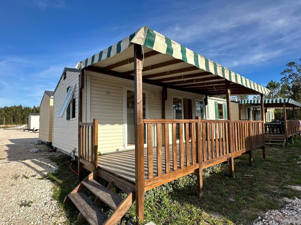 a tiny house with a porch and a deck at Surya's Bungalow in Pataias