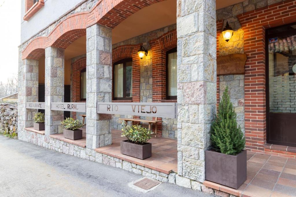 a building with potted plants on the side of it at Hotel Rural Rio Viejo in Cubillas de Arbas