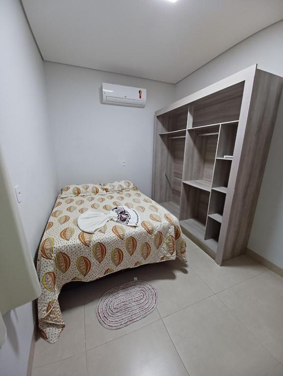 a small bedroom with a bed and a book shelf at Flat mobiliado in Sinop