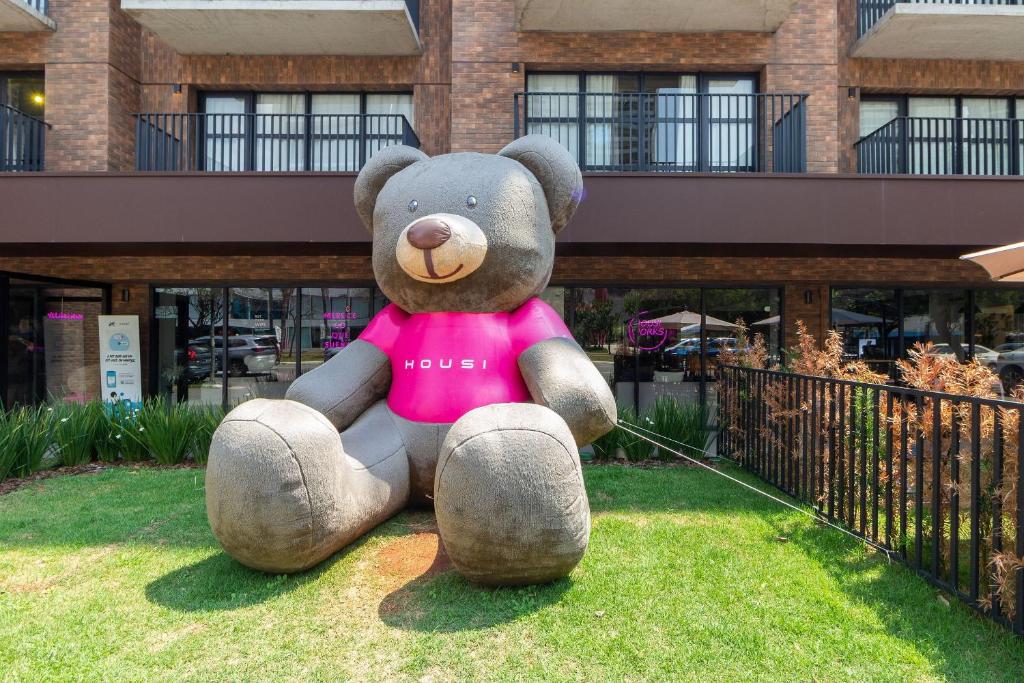 a large teddy bear sitting on the grass at Housi Boutique Faria Lima By Belong in Sao Paulo