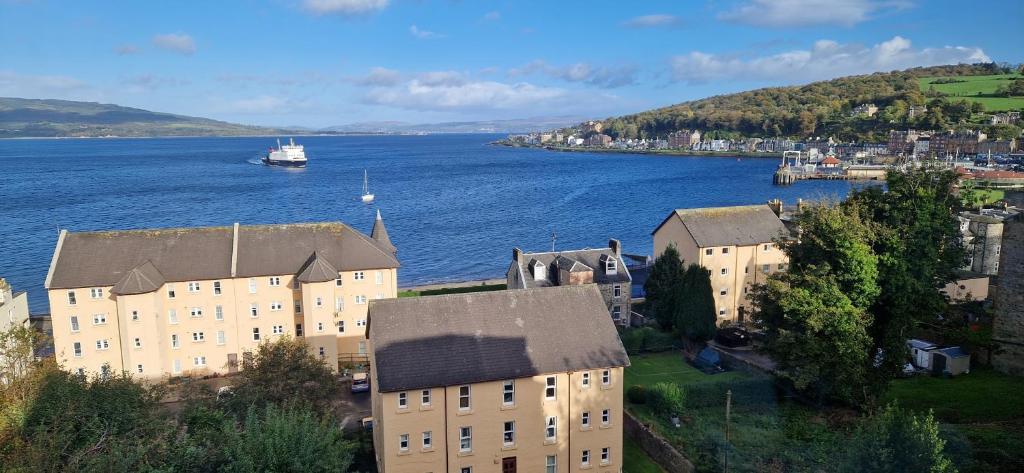 a large building next to a body of water with a boat at Entire Apartment, Rothesay, Isle of Bute in Rothesay