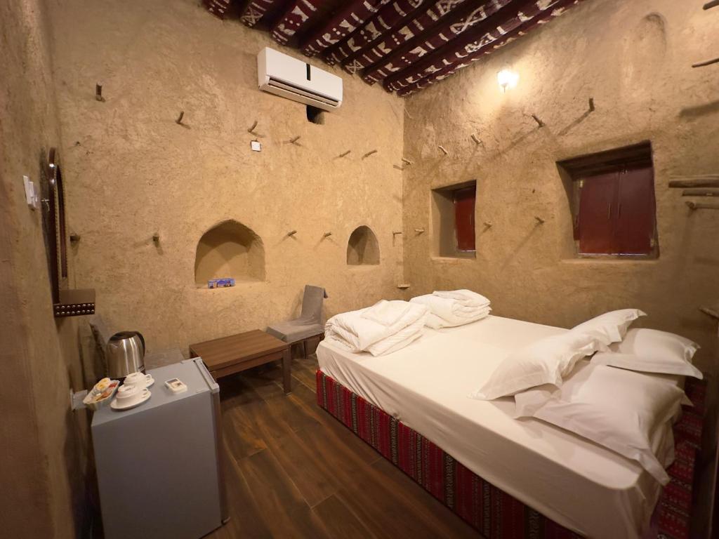 a bedroom with a bed in a stone wall at AL Hamra Heritage Inn in Al Ḩamrāʼ