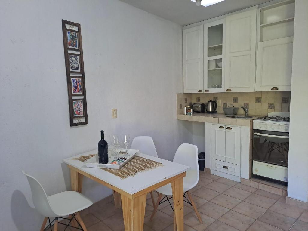 a kitchen with white cabinets and a table and chairs at Rincón Verde Chacras de Coria in Ciudad Lujan de Cuyo