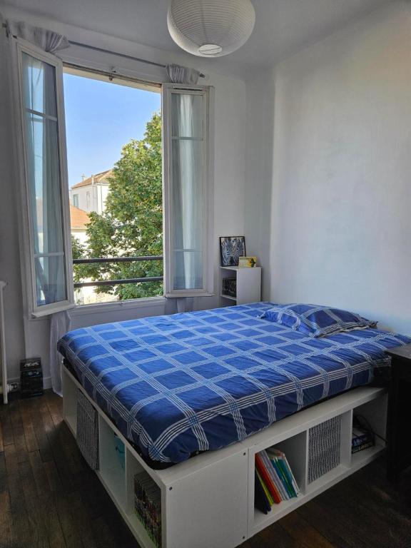Ce lit se trouve dans un dortoir doté d'une grande fenêtre. dans l'établissement Maison de ville avec jardin., à Courbevoie