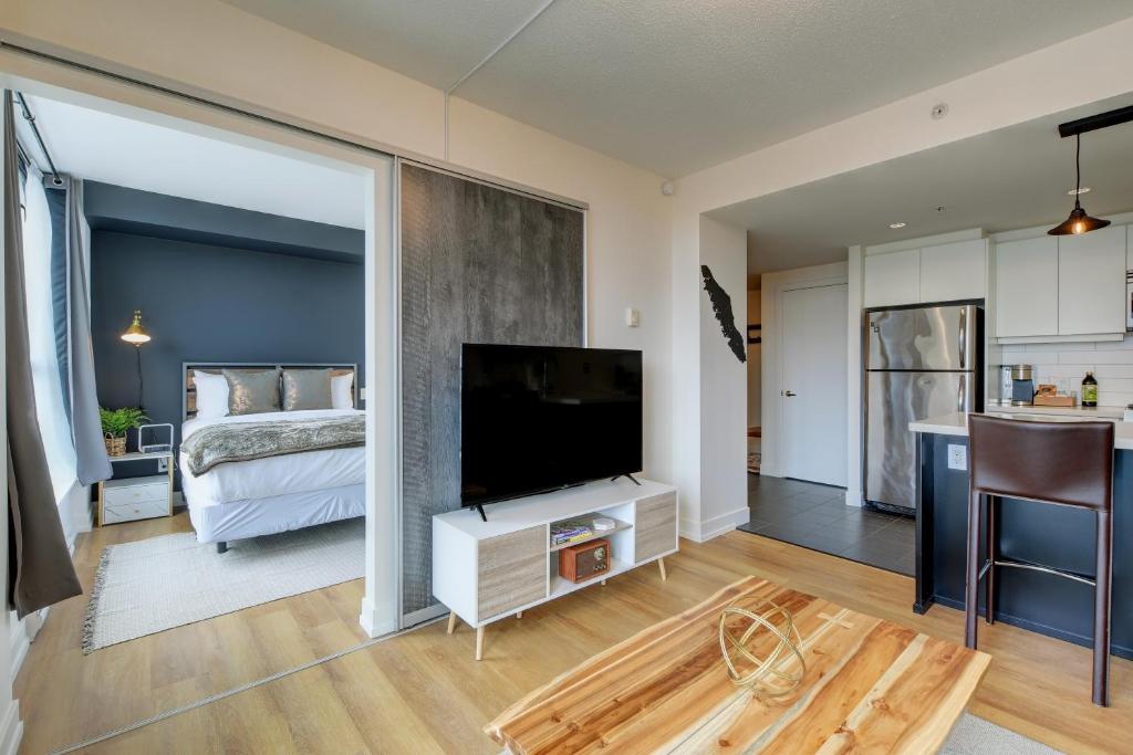 - un salon avec une télévision et un lit dans l'établissement Coastal Creative Condo, à Victoria