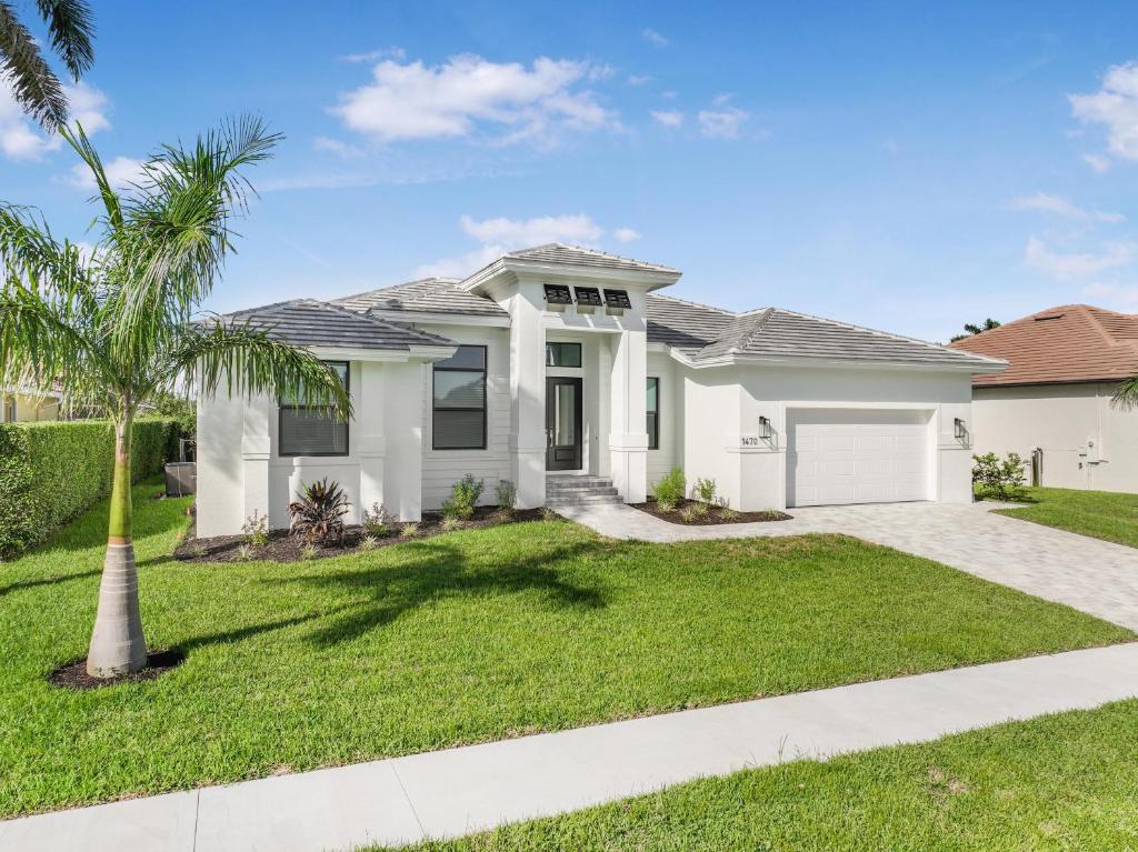 una casa blanca con una palmera en el patio en Marco Coastal Luxury | Pool, Spa and Outdoor Kitchen, en Marco Island
