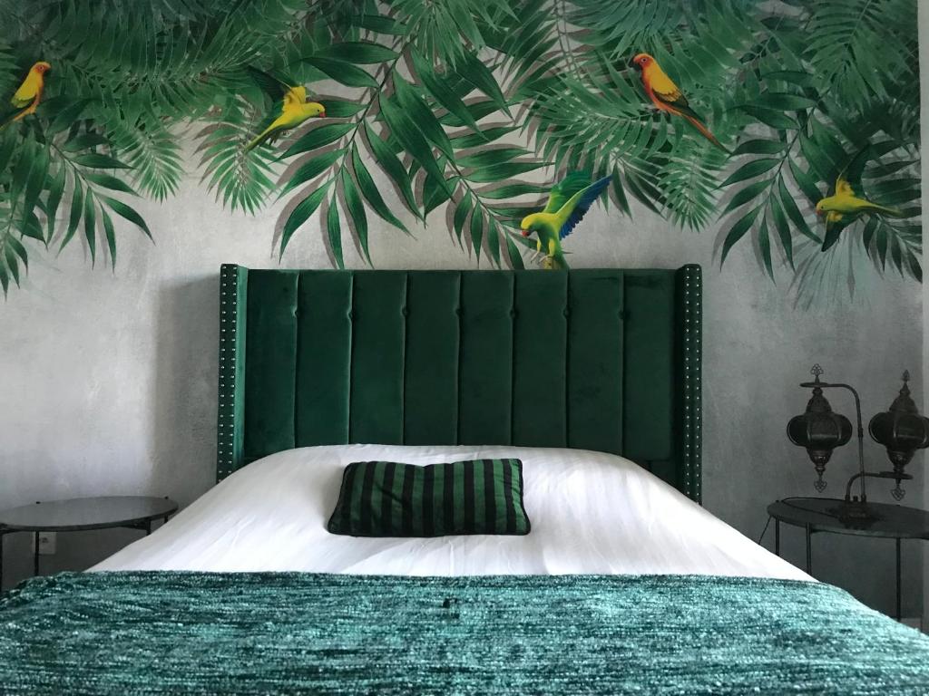 a bedroom with a bed with a green head board at Le chant des oiseaux - Au pied de la voie cyclable in Crévéchamps