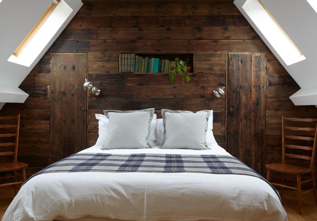 1 dormitorio con 1 cama y paredes de madera en The Old Barn at Moor Farm, en Godshill