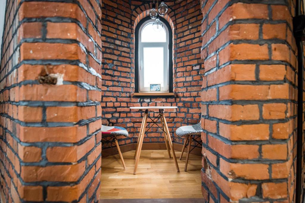 a brick room with a table and chairs and a window at Przytulny Apartament Z Wieżą in Gliwice