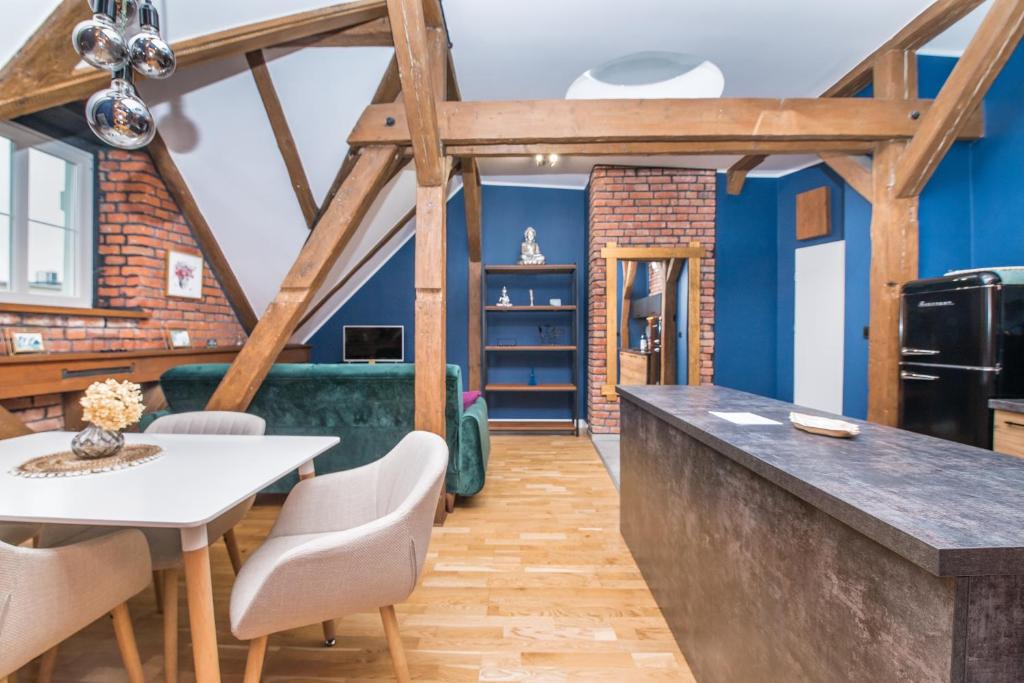 a kitchen and dining room with blue walls and wooden beams at Uroczy Apartament Gliwice in Gliwice