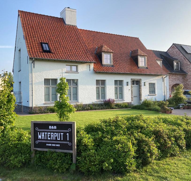 a white house with a sign in front of it at B&B Waterput 1 in Stalhille