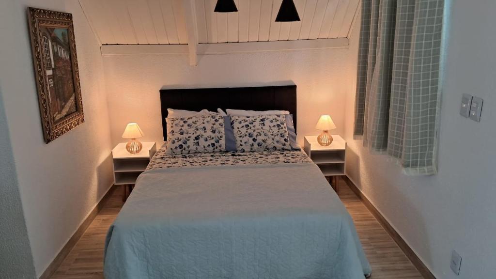 a bedroom with a large bed with two lamps at Meu Chalé in Miguel Pereira