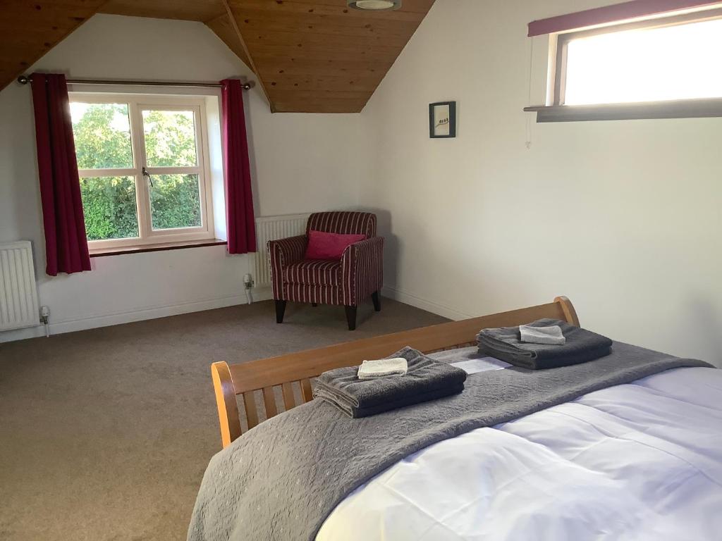 um quarto com uma cama, uma cadeira e uma janela em Stable Cottage em Blaenporth