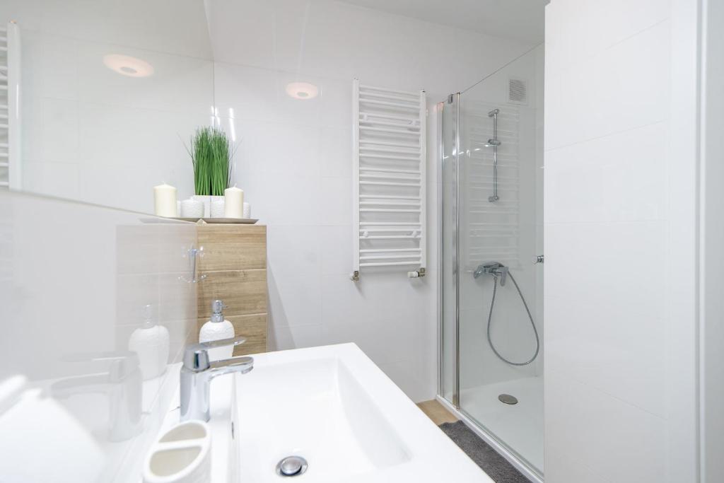 een witte badkamer met een douche en een wastafel bij Waterline Apartamenty Kołobrzeg in Kołobrzeg