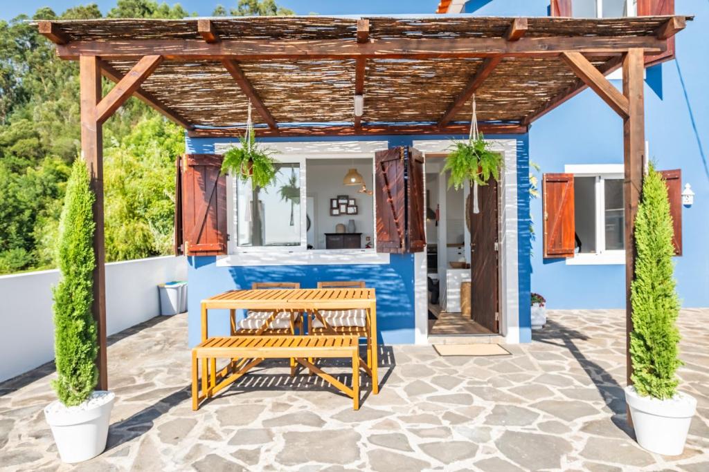 pérgola de madera con mesa y bancos en el patio en Blue House - By Wehost, en Ponta do Sol