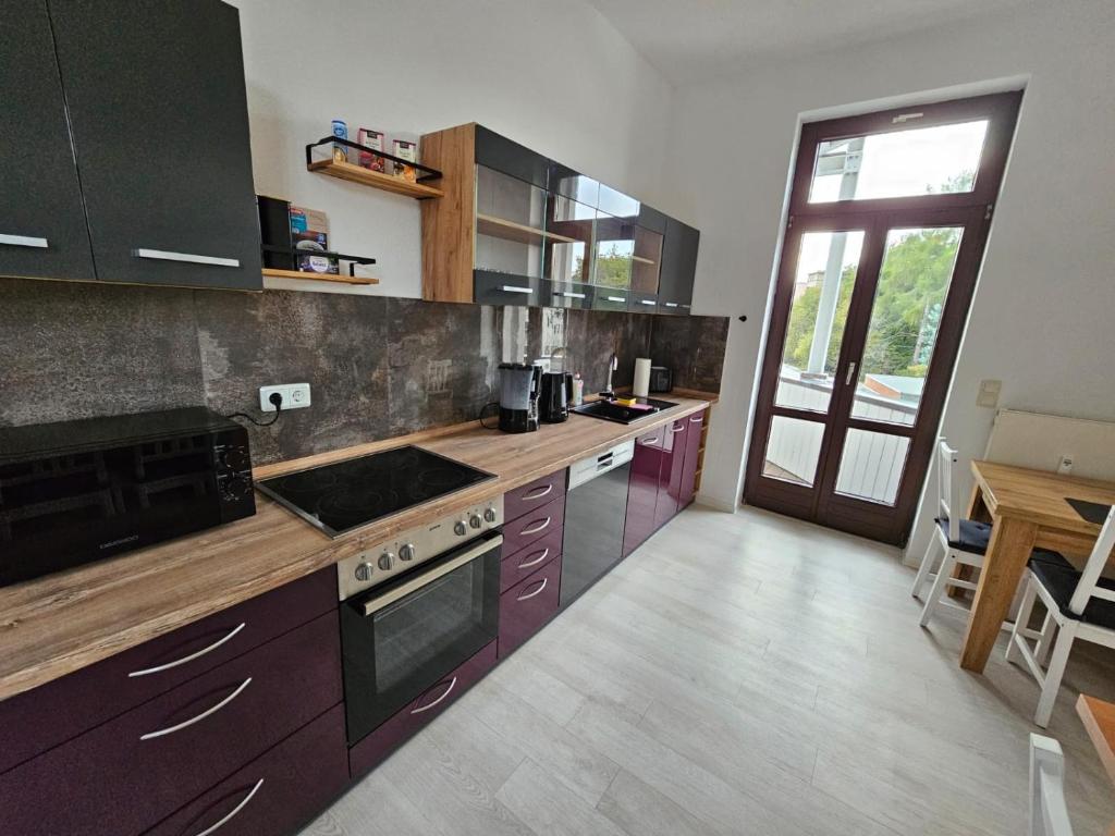 una cucina con armadietti viola e piano cottura con forno di Großzügige Ferienwohnung mit Balkon a Chemnitz