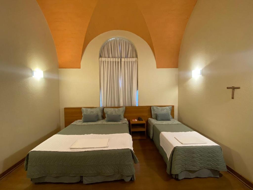 two beds in a room with a window at Pousada do Bom Jesus in Aparecida