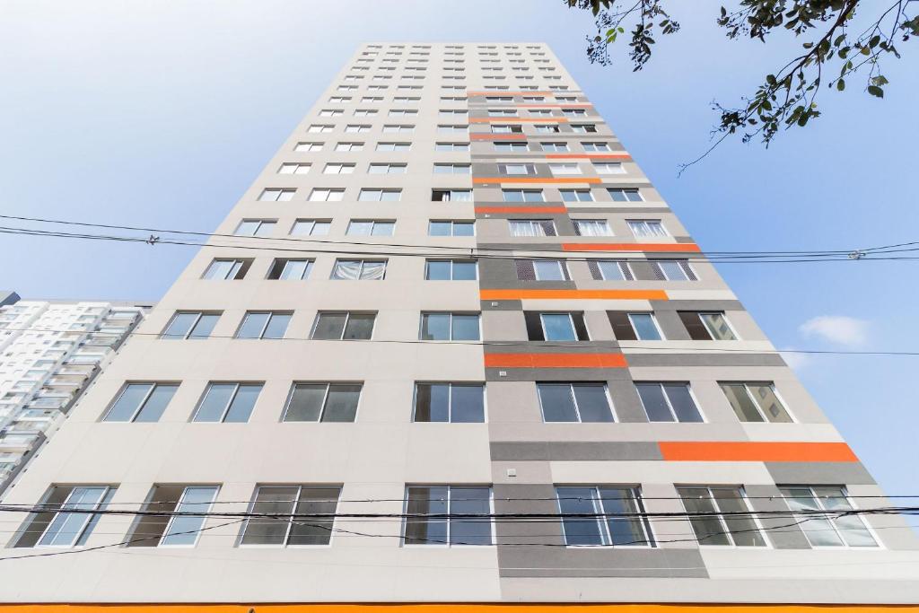 a tall white building with orange and gray windows at Canal do Anfitrião | Studios delicinhas in Sao Paulo