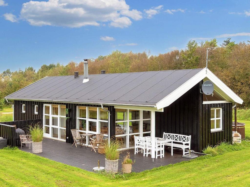uma casa negra com um deque e uma mesa em Three-Bedroom Holiday home in Øster Assels 3 em Sillerslev