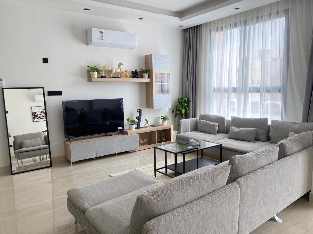 un soggiorno con divano e TV a schermo piatto di شقق عبية الفندقية a Riyad
