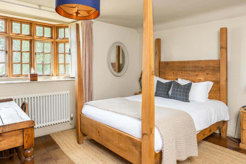 a bedroom with a four poster bed and a desk at The Ebrington Arms in Chipping Campden
