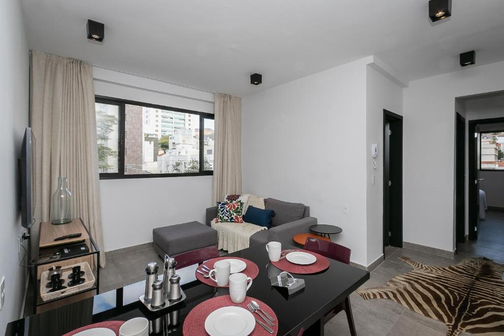 uma sala de estar com uma mesa e um sofá em Moderno apartamento, 2 quartos em Belo Horizonte