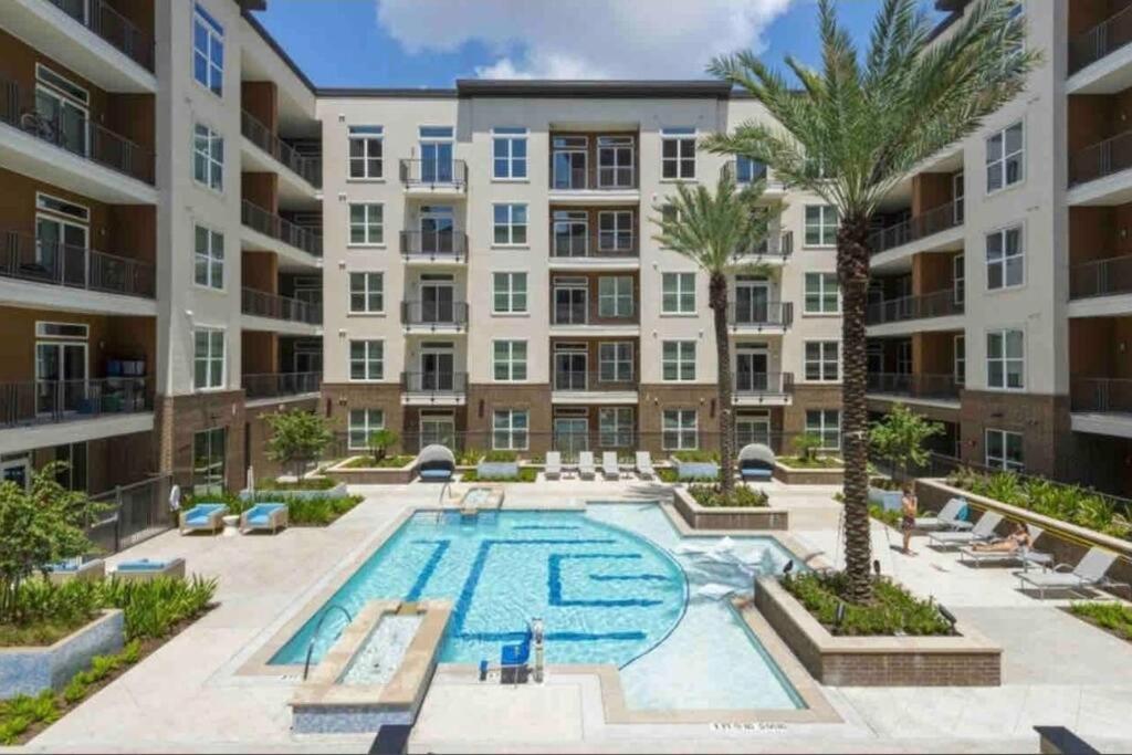 an apartment building with a pool and palm trees at Luxury Living Downtown Houston Kingbed. in Houston