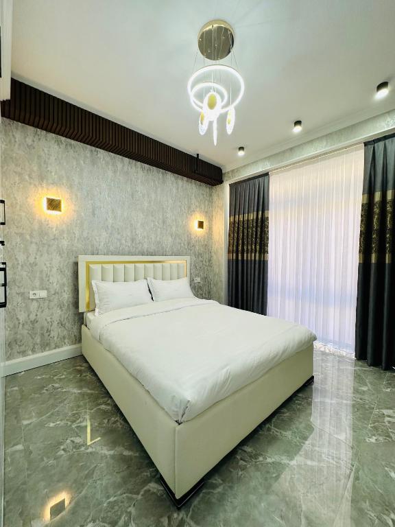 a bedroom with a large white bed and a chandelier at KERUEN SARAY APARTMENTS 20/2 in Türkistan