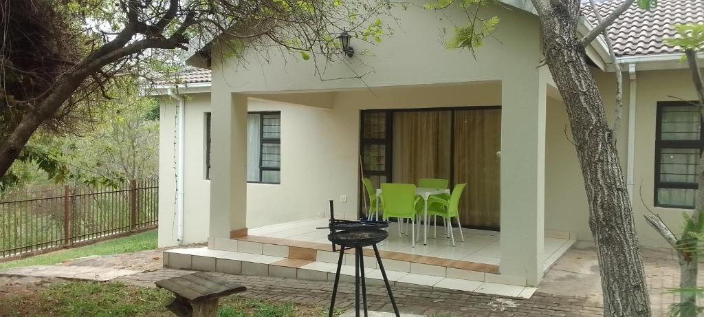 Cette maison dispose d'une terrasse avec une table et des chaises. dans l'établissement Sand River Cottages, à Hazyview