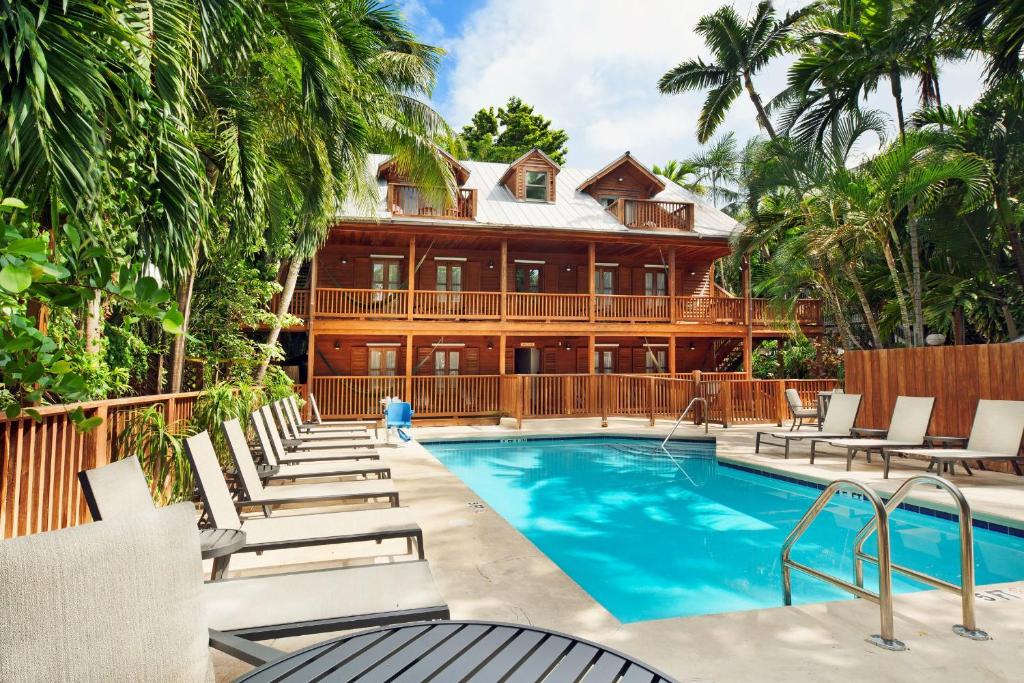 a resort pool with lounge chairs and a building at Island City House in Key West