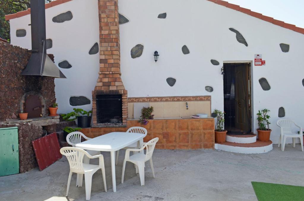 eine Terrasse mit einem Tisch, Stühlen und einem Kamin in der Unterkunft Casa Sendero de Taidia in San Bartolomé de Tirajana