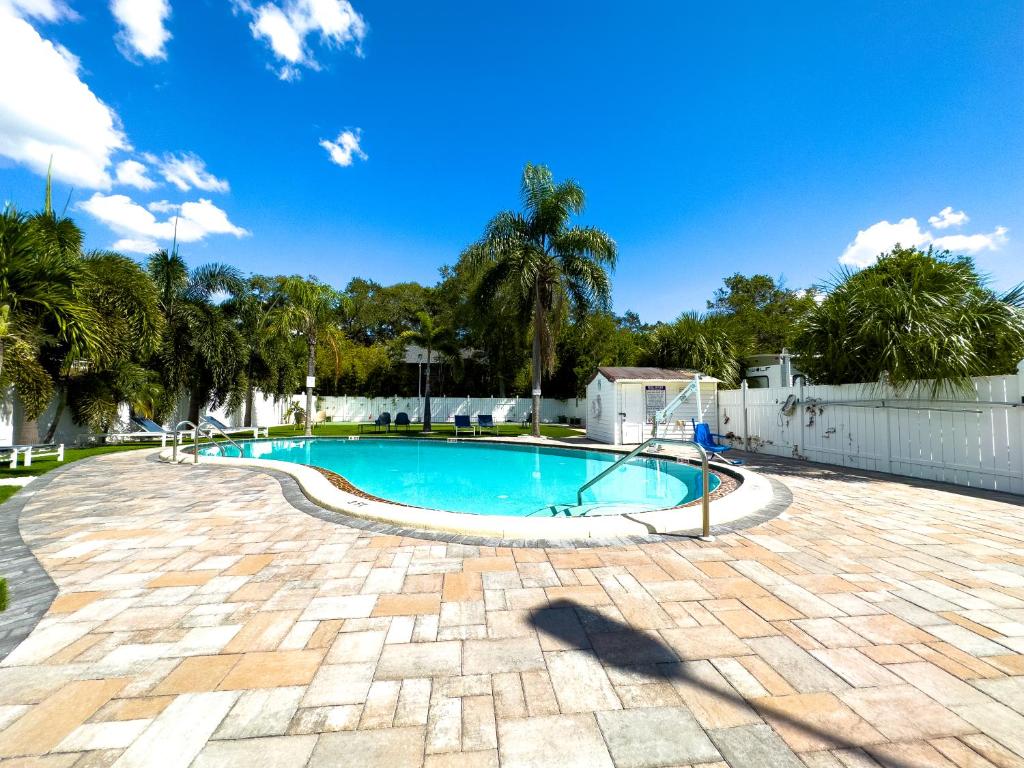 a swimming pool in a yard with a fence and trees at 2 Q Apt W Shared Pool 10 Min Clearwater Beach 4 in Clearwater