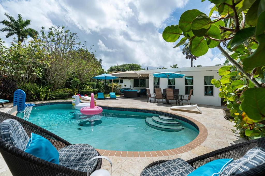 Exclusive Miami House: Your Private Pool Paradise في Biscayne Park: مسبح وكراسي ومنزل