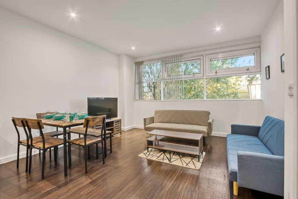 a living room with a couch and a table with chairs at Heathrow 2-Bedroom Urban Oasis in London