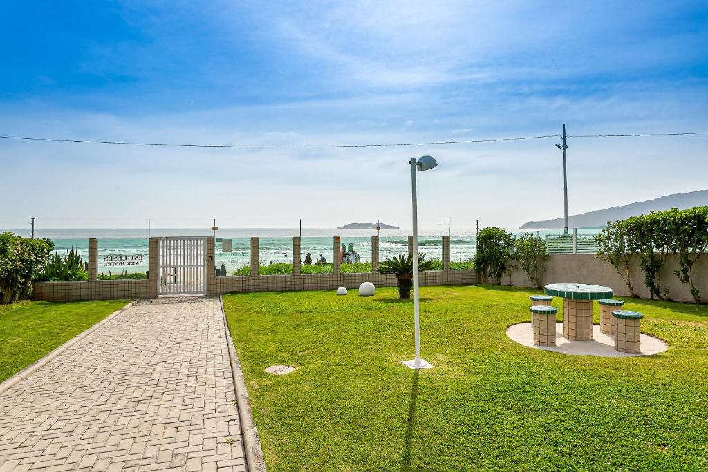 um parque com uma mesa e bancos e o oceano em Apto em condomínio pé na areia, c/ piscina MHR308 em Florianópolis