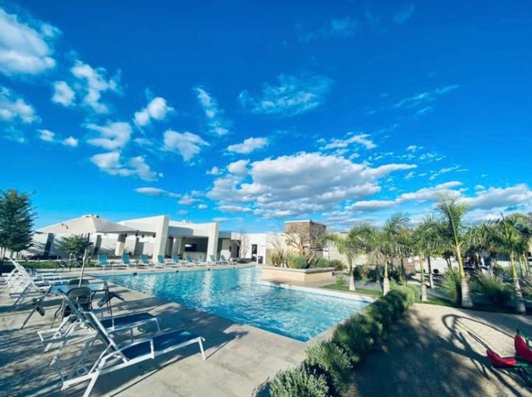 a large swimming pool with chairs and a blue sky at Casa Valtierra, La Paz in La Paz
