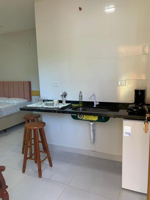 une cuisine avec un évier et un comptoir avec un tabouret dans l'établissement Lavínia loft 5, à Búzios
