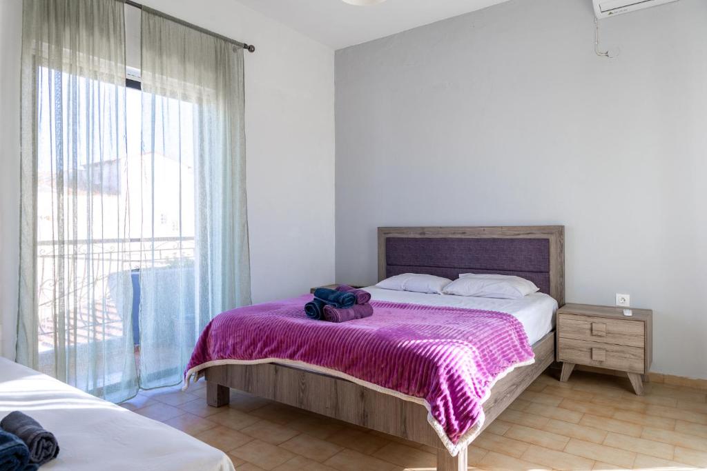 - une chambre avec un lit et une couverture violette dans l'établissement Delight apartment LA, à Larissa