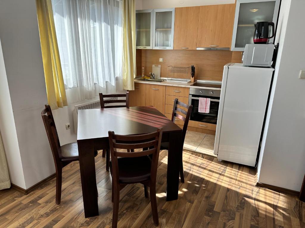 una cucina con tavolo, sedie e frigorifero di Ramada 2 - Apartment a Bansko