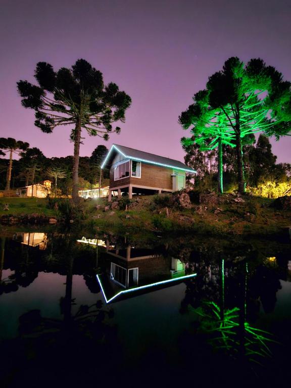 une maison assise sur la rive d'un lac la nuit dans l'établissement Chalé do Lago Urupema SC, à Urupema