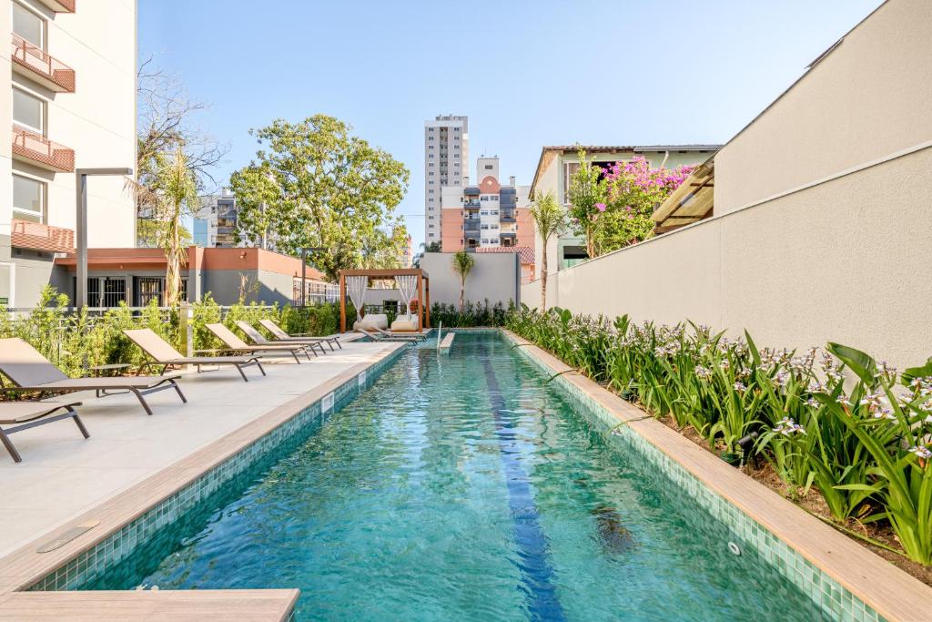 a swimming pool with chairs and a building at Charlie Connect PUC in Porto Alegre