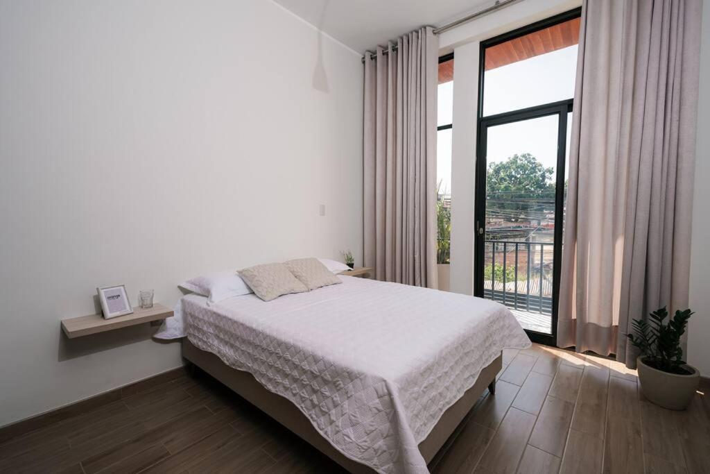 ein Schlafzimmer mit einem Bett und einem großen Fenster in der Unterkunft CASA MONA 2 - Apartamento en Tarapoto in Tarapoto
