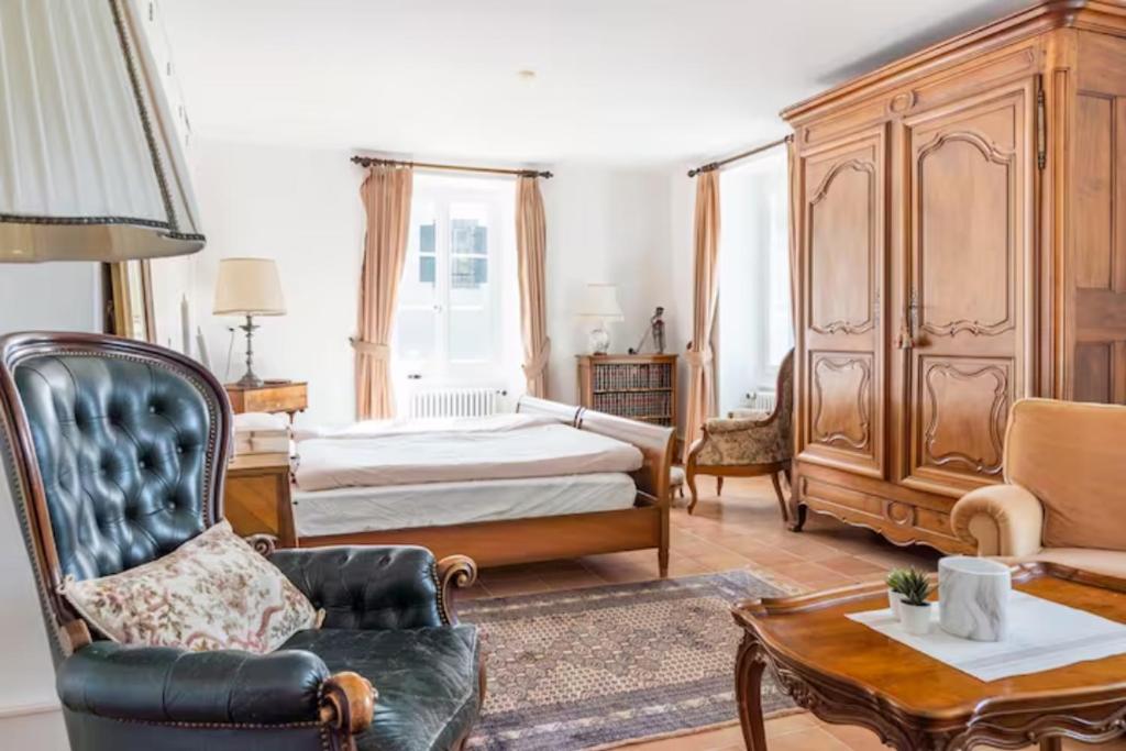 a bedroom with a bed and a chair and a table at Chambre d'hôte au milieu des vignes avec magnifique vue sur le lac et jardin in Féchy
